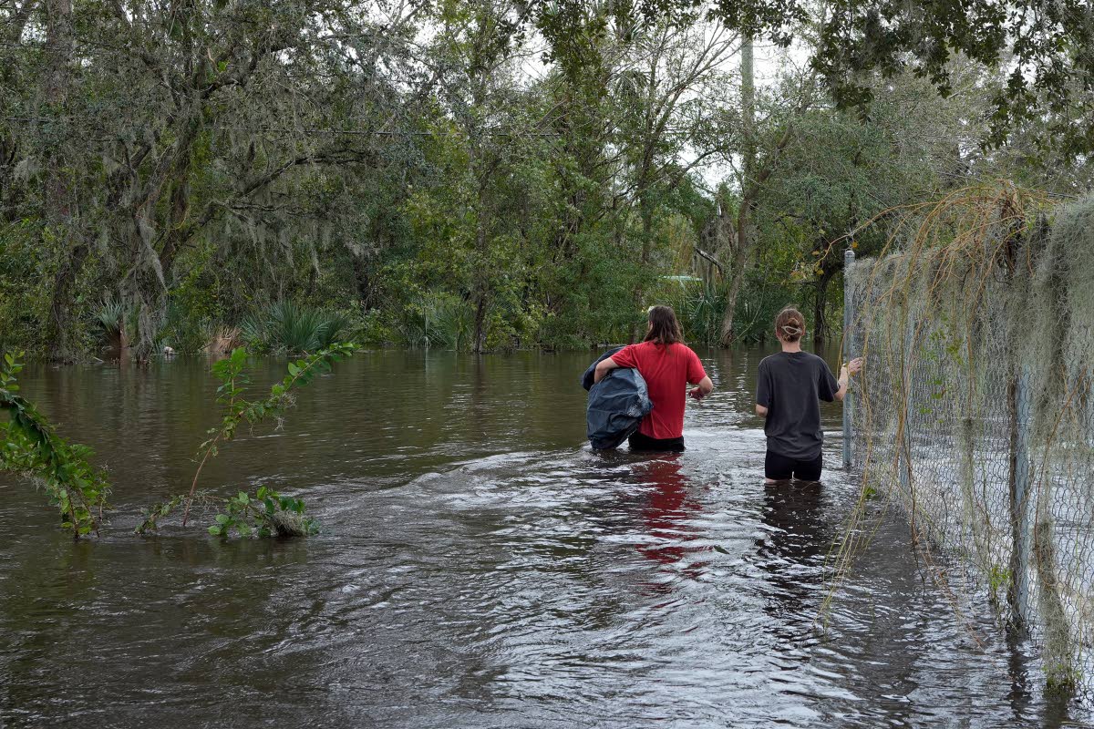 Connor Hughes and Kaylee Swenson walk through floodwaters from the Alafia River caused by Hurricane Milton, October 11, 2024, in Lithia, Florida.