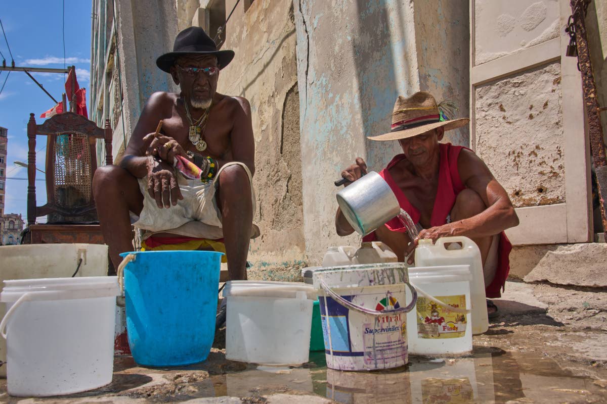 Oscar Joaquín López (left) and his housemate Wilfredo Cisneros Duarte collect water from a street pipe in Havana, Cuba, on September 7.