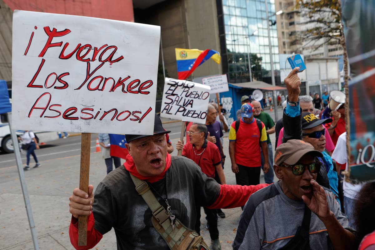 A man holds a sign with a message that reads in Spanish;  "Yankee out, murderers", during a protest in Caracas on Saturday, August 29 against President Donald Trump's deal giving the United States a stake in Venezuela’s oil reserves.