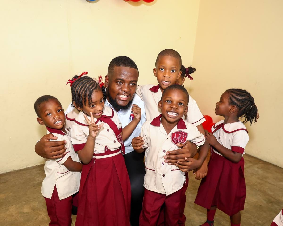 Antoine Lodge, founder of the Dream Big for Youth Foundation, poses for a photo with students at his alma mater, where he launched a breakfast programme on Tuesday.