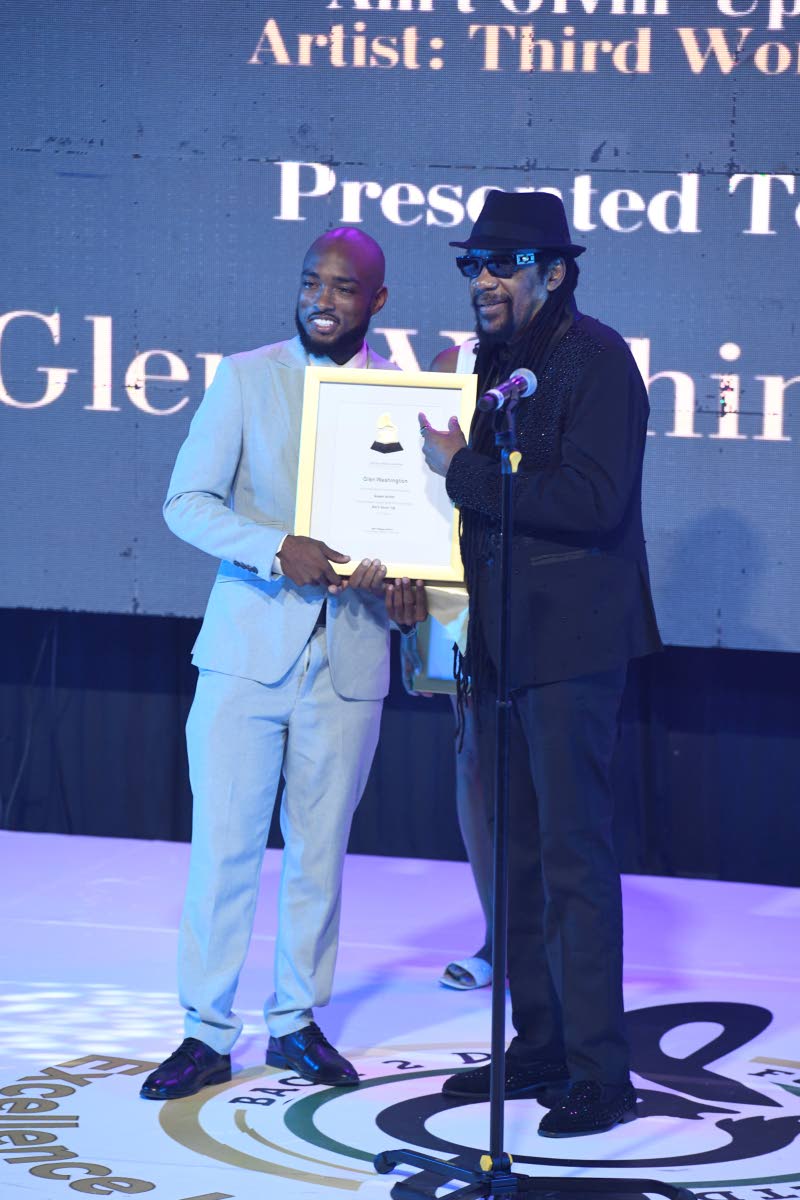 Glen Washington (right) receives Grammy Certificates for his contributions to Capleton’s Still Blazin’ and Third World’s Ain’t Givin’ Up. Joel Laing, the event’s sponsorship manager, makes the presentation.