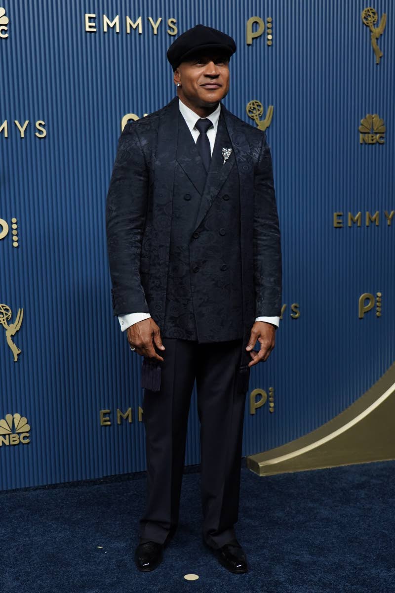 LL Cool J keeps things classic with a twist, stepping onto the Emmy carpet in a dark, patterned double-breasted suit, matching tie, and flat cap. A statement brooch and polished accessories completes the look.