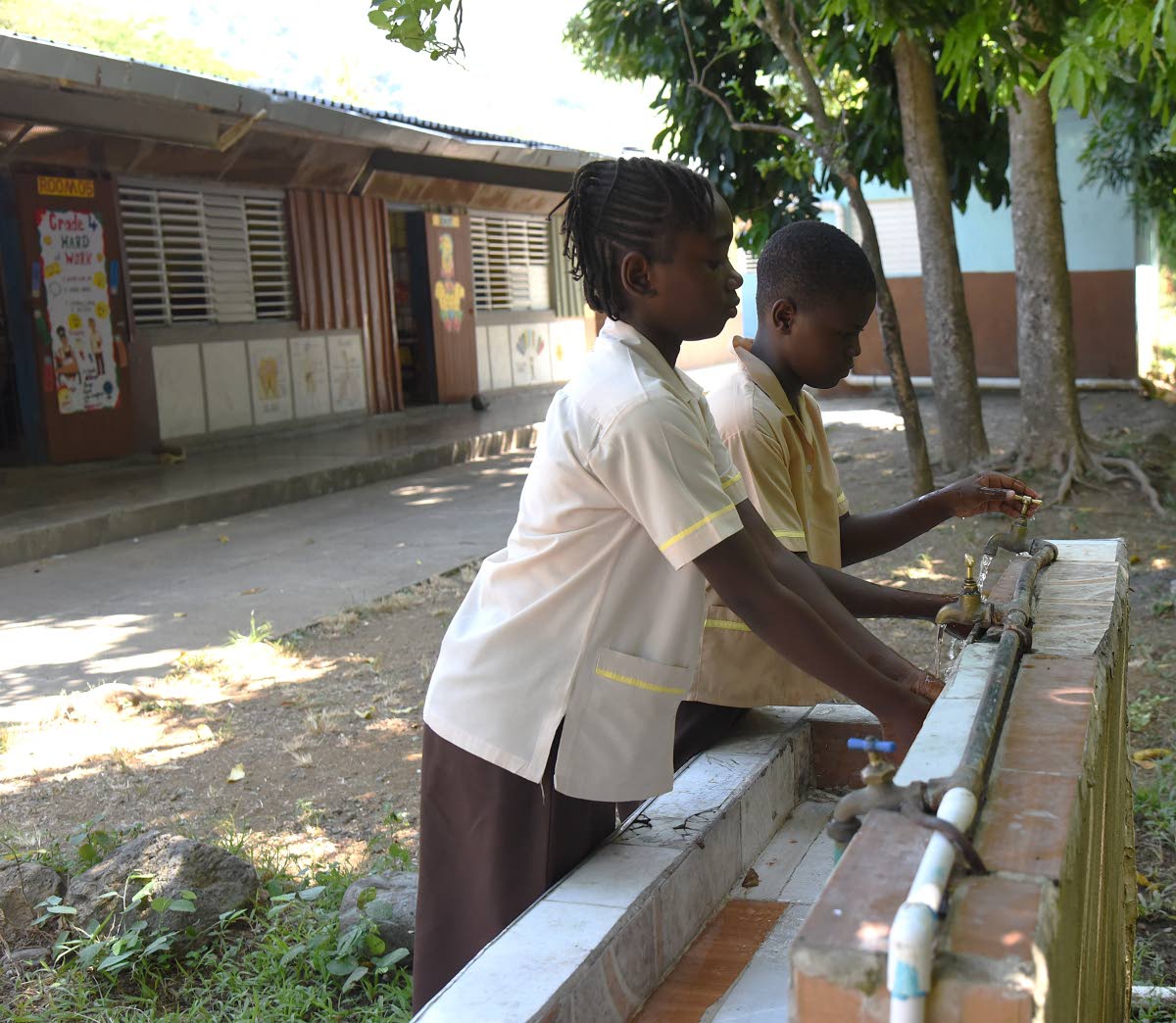 Shenece Paul (left) and Makonen Millwood (right), grade-five students at Bethesda Primary School in Llandewey, St Thomas, are able to wash their hands despite limited water at the school. 
