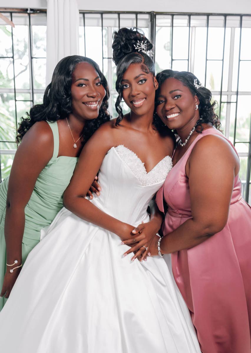 The blushing bride is supported by her sister, Monique Hamilton (left), and mother, Renee Smith Grant.