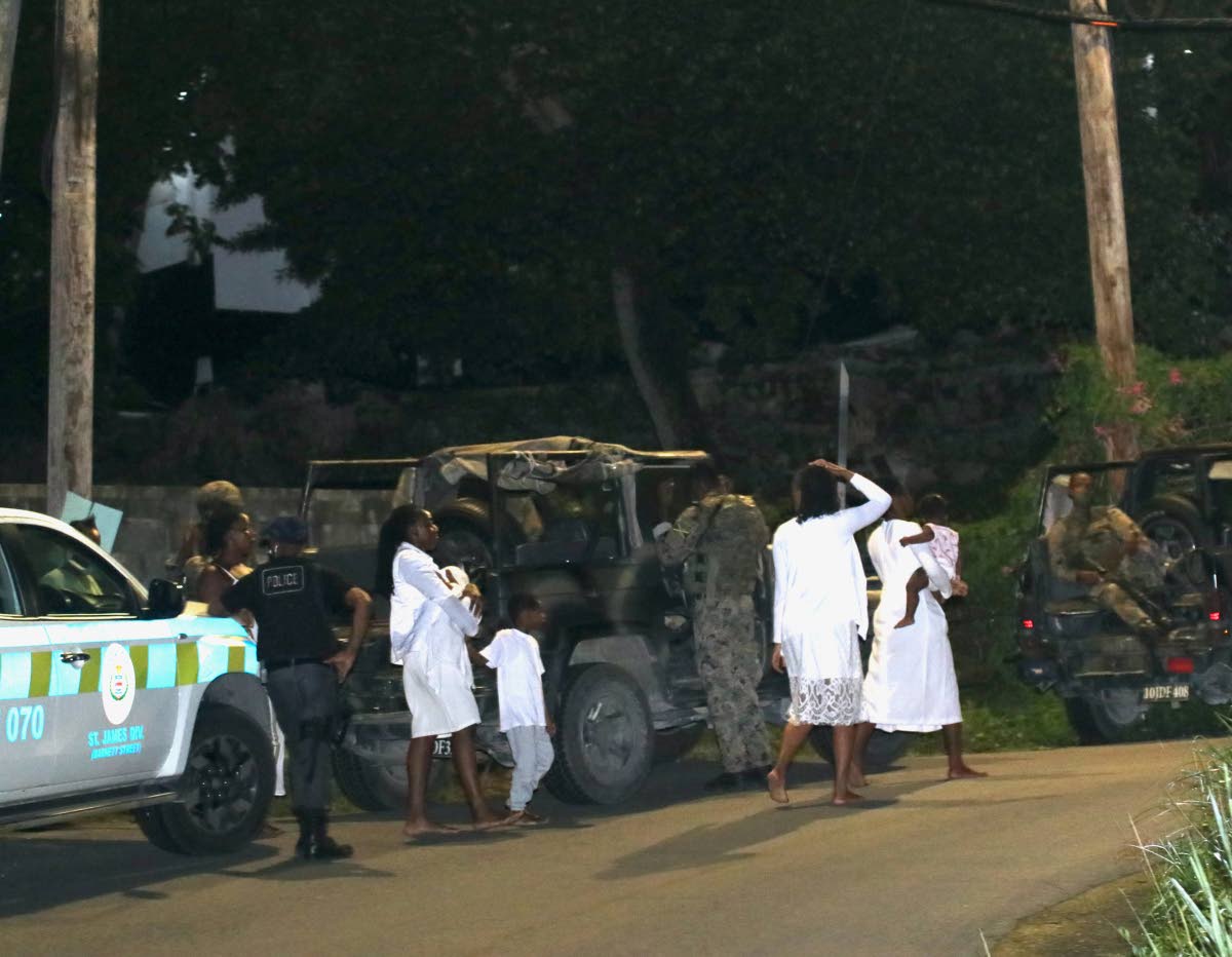 Police and soldiers with members of the Pathways International Kingdom Restoration Ministries outside the Montego Bay-based church, where a deadly service unfolded on October 17, 2021.