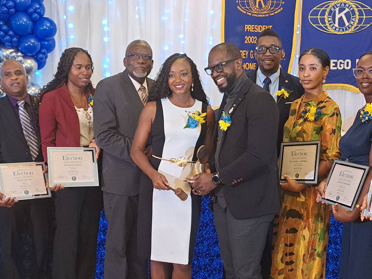 Jo-Dane Russell Guerra (centre), newly installed president of the Kiwanis Club of Montego Bay, receives the presidential instruments from lieutenant governor Jerome Johnson (fourth right) during the club’s 60th-anniversary luncheon and installation cerem