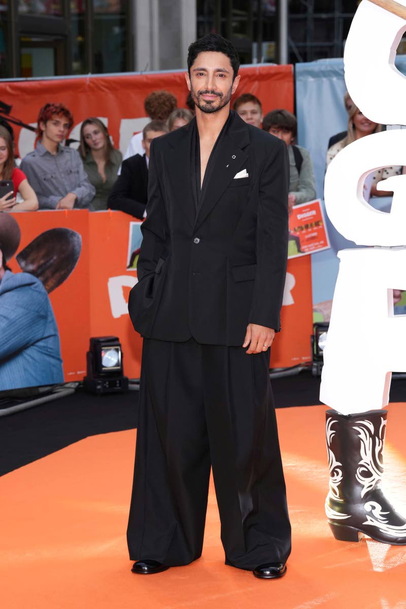 Riz Ahmed steps out in an all-black look featuring a single-breasted jacket and wide-leg trousers.