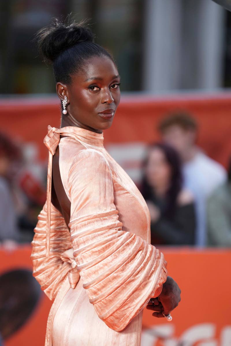 Jodie Turner-Smith gives photographers a peek at the dramatic ruched sleeves and delicate open-back design of her custom Louis Vuitton gown.