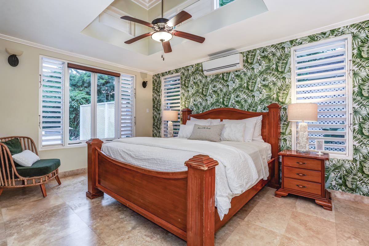 The primary bedroom surprises with its centrally raised ceiling structure, enclosed by windows.