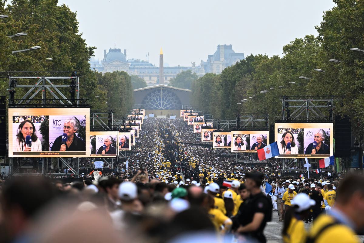 People wait for Pope Leo XIV on the Champs Elysees avenue before a mass at Place de la Concorde in Paris on Saturday.