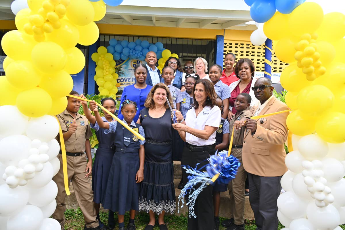 American Friends of Jamaica President Wendy Hart (fourth left) cuts the ribbon officially handing over the rebuilt Cove Primary in Hanover, along with Heidi Clarke of Sandals Foundation (second right) and  students and members of management of the school l