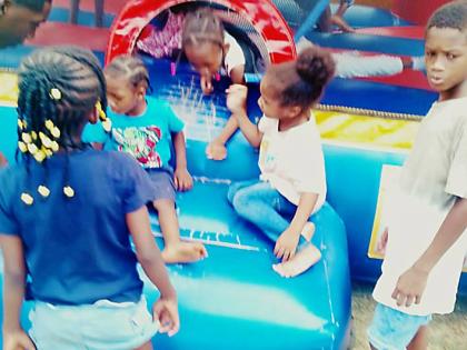 Children wait their turn to play inside the bouncy castle at a back-to-school treat in Clark’s Town, Clarendon.