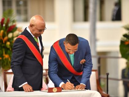 Governor General Sir Patrick Allen (left) watches as Prime Minister Dr Andrew Holness signs the Instrument of Appointment during his Swearing-In Ceremony at King’s House in St Andrew on Tuesday.