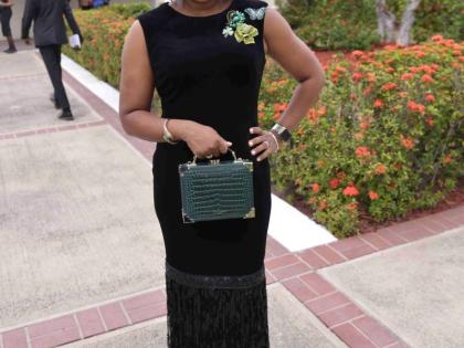 Senator Dr Dana Morris Dixon makes a strong statement in a black velvet midi dress with a tasselled hem, pairing the look with emerald accents.