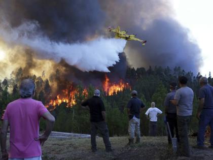 Villagers watch a firefighting plane drop water to stop a raging forest fire reaching their houses in Portugal.