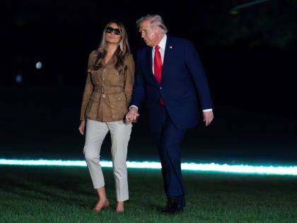 President Donald Trump holds hands with first lady Melania Trump as they walk on the South Lawn upon their arrival to the White House, in Washington on Thursday.