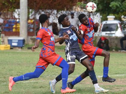 Ian Allen/Photographer 
Jamaica College’s (JC) Dwayne Burgher (centre) tries to get between Camperdown’s Roberto Menzie (left) and Nathaniel Grappie during their ISSA/WATA daCosta Cup football match at the Alpha Boys playing field yesterday. JC won 2-0