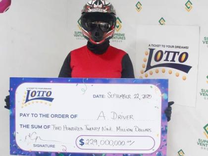 'A Driver', the first Lotto millionaire of 2025 proudly displays her cheque during the handover at the Supreme Ventures Limited Twin Gates store.