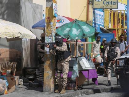 Police officers patrol a street during an exchange of gunfire between gangs and police in Port-au-Prince, Haiti.