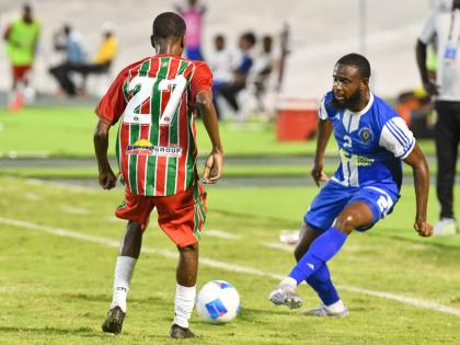 Mount Pleasant’s Gadail Irving (right) passes the ball between the legs of Robinhood FC’s Don Turr during their Concacaf Caribbean Cup Match at the National Stadium on August 19.