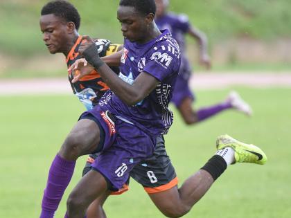 Kingston College’s Deshawn Byfield (right) turns away from Tivoli’s Malachi Rose during their ISSA/WATA Manning Cup clash at the Stadium East field yesterday. KC won the game 4-0.