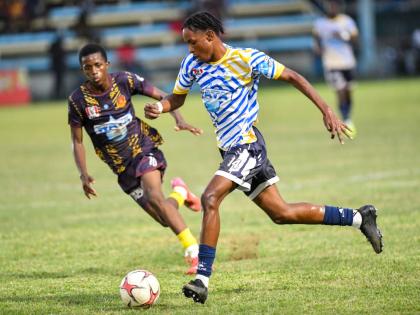 Jamaica College’s Malique Bucknor (right) drives the ball forward while being chased by St Andrew Technical High School’s Shankeno Grant during their ISSA/WATA Manning Cup clash at the Drewsland Stadium on September 27.