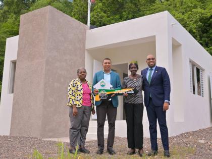 Prime Minister, Dr Andrew Holness (second left) presents New Social Housing Programme (NSHP) recipient Gloria Williams (second right) with a symbolic key during the handover of her new home in Red Hills, St Andrew, on October 15. Sharing in the moment are 