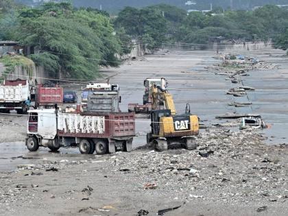 Heavy equipment and trucks are seen at Sandy Gully clearing debris and garbage ahead of Tropical Storm Melissa.