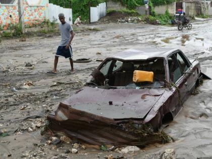 A pedestrian looks at a flooded car in the aftermath of Hurricane Melissa in Petit-Goave, Haiti, Thursday, October, 2025. 