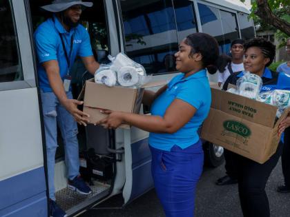 Flow team members (from left) Adrian Stewart, Patrice Todd, and Katoya Mohalland pack essential supplies at Flow’s corporate offices in Kingston as they get ready to assist residents in St James who were impacted by Hurricane Melissa.