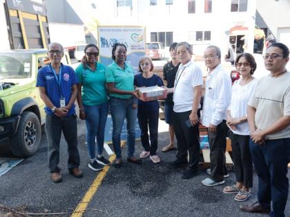 Abigail Whittaker-Clarke (second left) and Elecia Whittingham-Gayle (third left) collect a donation from the Burmese community, on behalf of the Western Regional Health Authority staff members. 