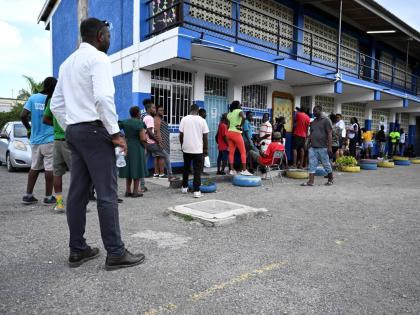 People are seen waiting outside a polling station at Morant Bay Primary School, St Thomas to cast their votes in September’s general election.