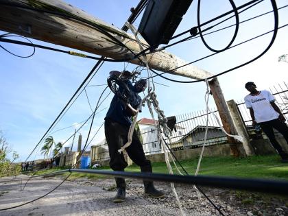 A man clears a roadway in Lacovia, St Elizabeth, after downed power poles blocked it during Hurricane Melissa.