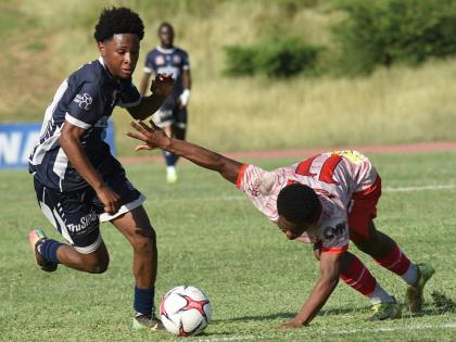Jamone Lyle (left) of Jamaica College dribbles past Mona High’s Nathaniel McCarthy during their Manning Cup second round match at the Stadium East field on Wednesday. The game ended in a 2-2 draw.