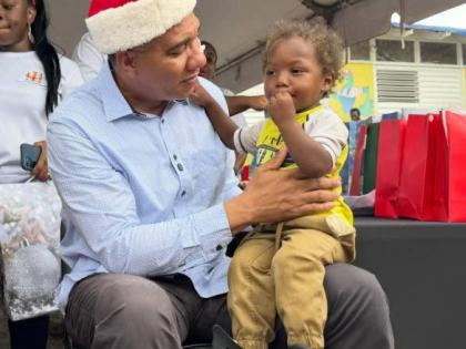 Prime Minister Dr Andrew Holness interacts with a young child at a Christmas kiddies treat at the Middle Quarters Primary and Infant School in St Elizabeth on December 13, 2025.