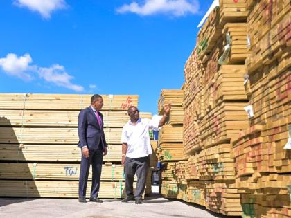 Prime Minister, Dr Andrew Holness (left), is shown lumber donated by Kemtek Development and Construction Limited in support of post-Hurricane Melissa recovery efforts, by Chairman and Managing Director, Sylvester Tulloch, during the handover of relief supp