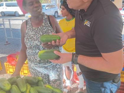 Dr Christopher Tufton, Member of Parliament for St Catherine West Central, speaks with vendor Annmarie Reid about cucumbers during the Green Acres Farmer’s Market in St Catherine on December 22, 2025. 