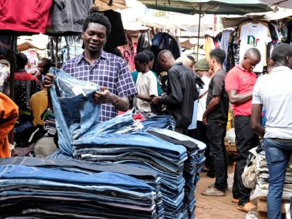 A second-hand clothes retailer folds second-hand jeans at his stall at Owino Market in Kampala, Uganda.