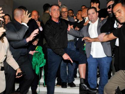 Brazil’s former President Jair Bolsonaro points to his electronic ankle monitor that the Supreme Court ordered him to wear, at Congress in Brasilia.