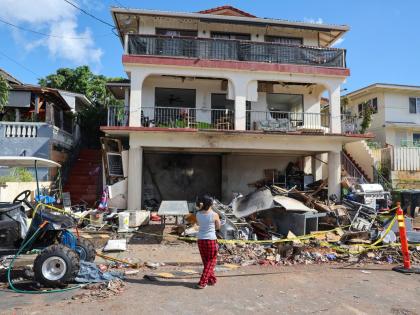  A woman stands in front of the home where a New Year's Eve firework explosion killed and injured people, January 1, 2025, in Honolulu. (AP Photo/Marco Garcia, File)