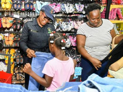Founder of the Shop with a Cop Initiative, Deputy Superintendent of Police Paulette Baker (left), provides guidance to Natalie Lindsay and her granddaughter, Mikayla Ledgister.
