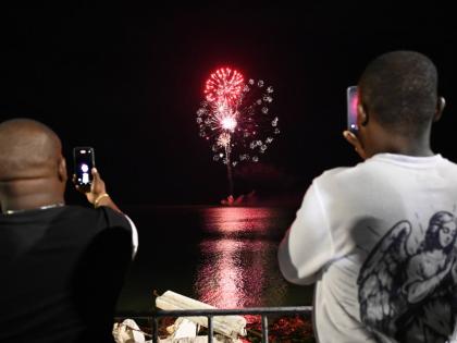 Two men photograph fireworks over Black River’s seafront.