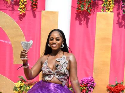 Regulatory specialist Jillesa Reid stands out in a vibrant purple ensemble that is both eye-catching and commanding. The sculpted top pairs seamlessly with the dramatic, textured pants, creating a look that feels powerful yet playful.