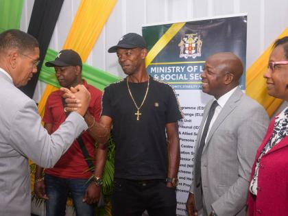 State Minister in the Ministry of Labour and Social Security, Donovan Williams (left), greets farmworker, Arnold Campbell (centre), at a send- off for seasonal agricultural workers to Canada, held at the Ministry’s Overseas Employment Centre on East Stre