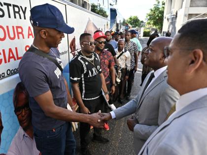 Pearnel Charles Jr, (second right) Minister of Labour  and Social Security, and Donovan Williams, (right) minister of state in the Ministry of Labour and Social Security of Jamaica, greet farm workers at the first send-off ceremony of farm workers to Canad