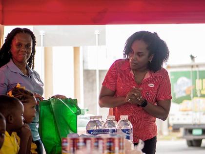 Salada Foods General Manager Tamii Brown (right) greets the mini packing line of Jebb Memorial Basic School students at Salada Foods headquarters on Bell Road. Looking on is Jebb Memorial Basic School Principal Leonie Salmon Wong-Sue.