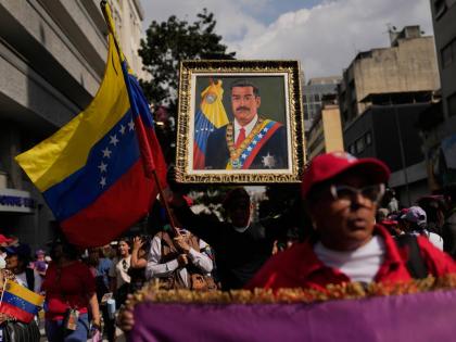 A government supporter holds an image of President Nicolás Maduro during a women’s march to demand his return in Caracas, Venezuela.