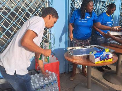 Brian Anderson (left), the president of the National Secondary Students’ Council, works with volunteers in an outreach initiative in Treasure Beach, St Elizabeth, one week after the passage of Hurricane Melissa.