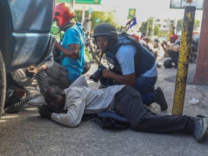 Journalists take cover from the exchange of gunfire between gangs and police in Port-au-Prince, Haiti.