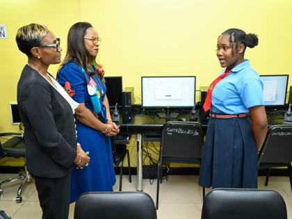 Member of Parliament for St Andrew West Rural Juliet Cuthbert Flynn (left) and Permanent Secretary in the Ministry of Education, Skills, Youth and Information, Dr Kasan Troupe, listen as Stony Hill Technical High School student Sabrina Davis shares details